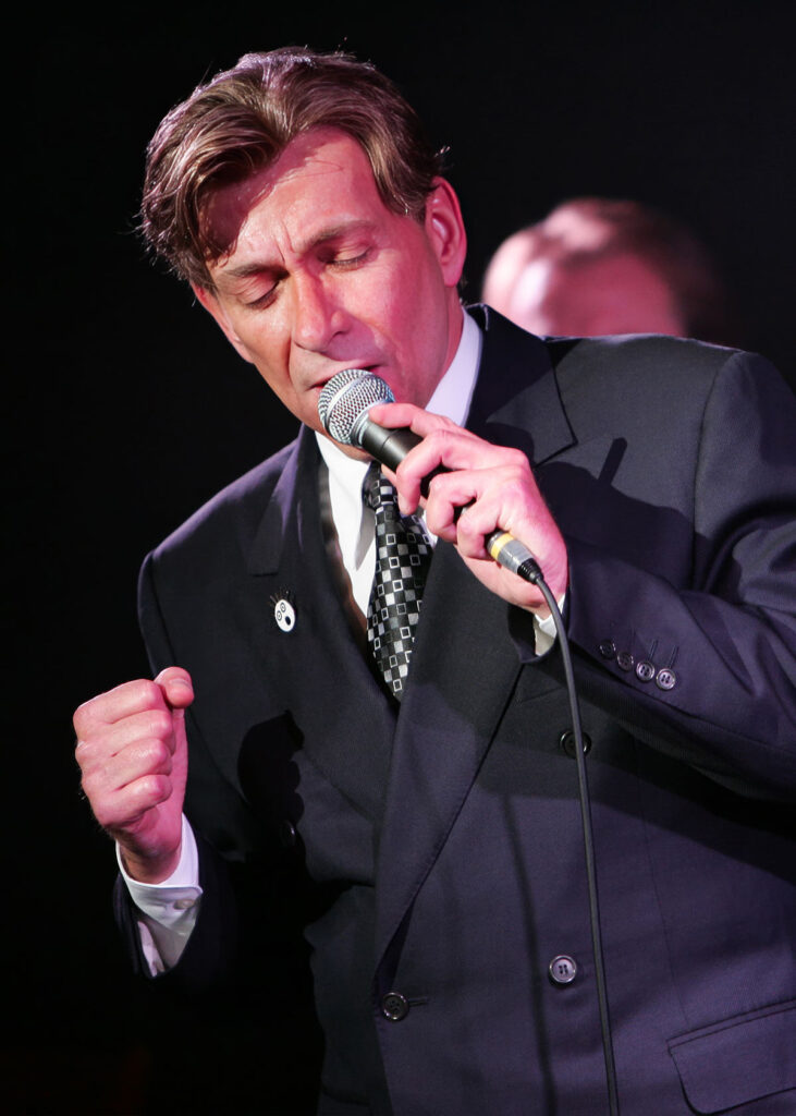 Bobby Caldwell singing into a microphone on stage